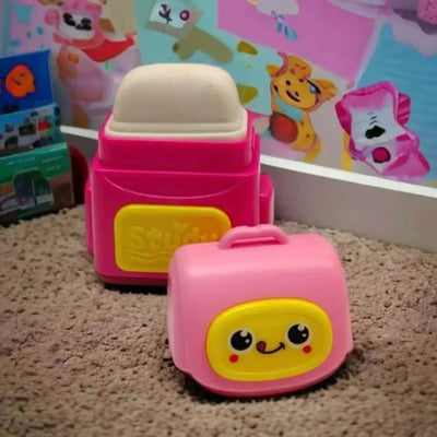Two pink toy suitcases with cartoon faces on a carpeted floor.