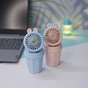 Pair of Usmile Toys hi-speed kids desk fans in light blue and pink, each featuring cute bunny ears and a 'hello' design on the grille, ideal for a child's personal space." www.usmile.toys