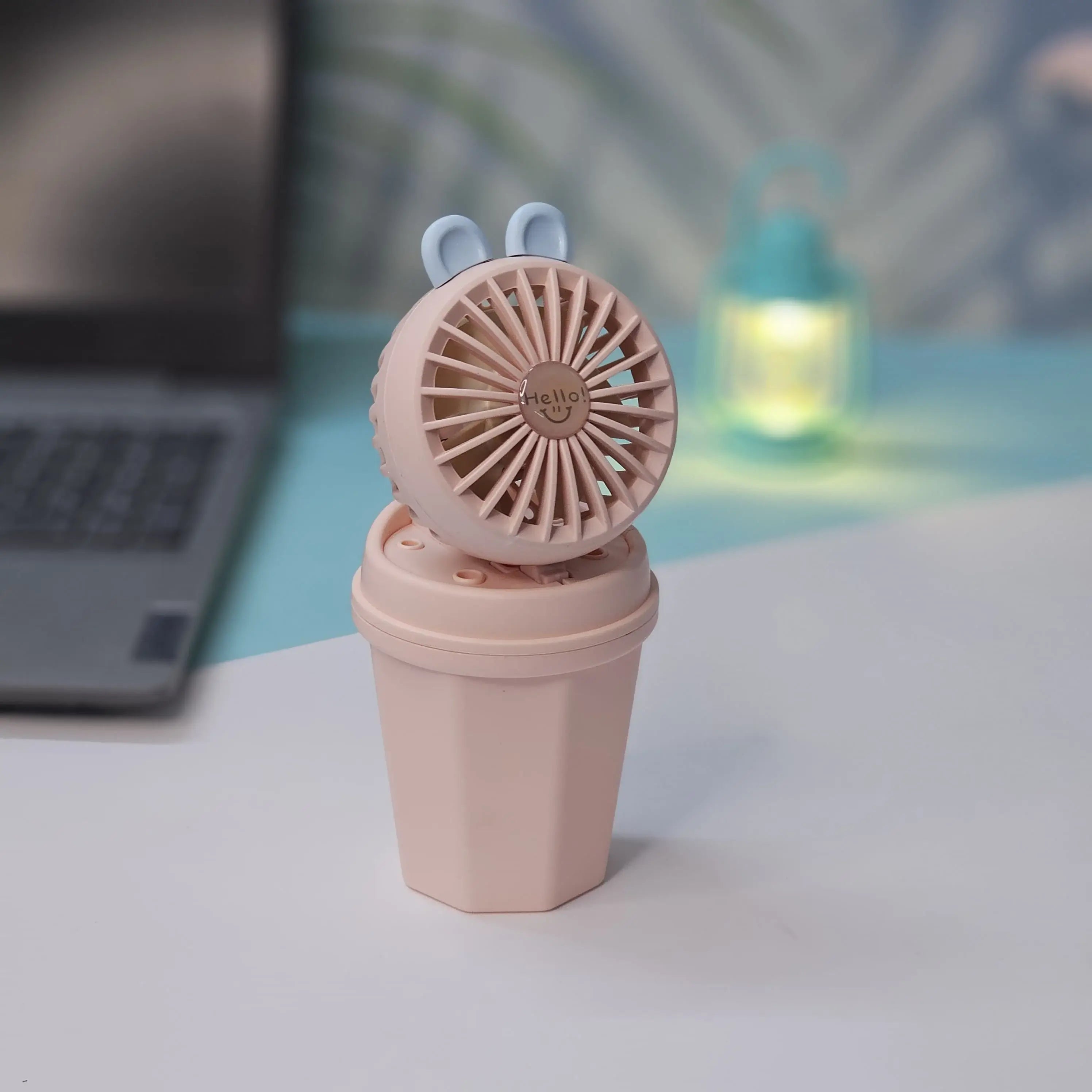Front view of two Usmile Toys Hi Speed Kids Desk Fans, a blue and a pink one, showing their round grilles with a 'hello' emoji and charming bunny ears, suitable for adding a breeze and fun to any desk."