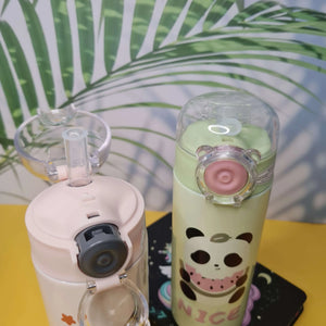 Two colorful water bottles with unique designs on a surface with a leafy background.