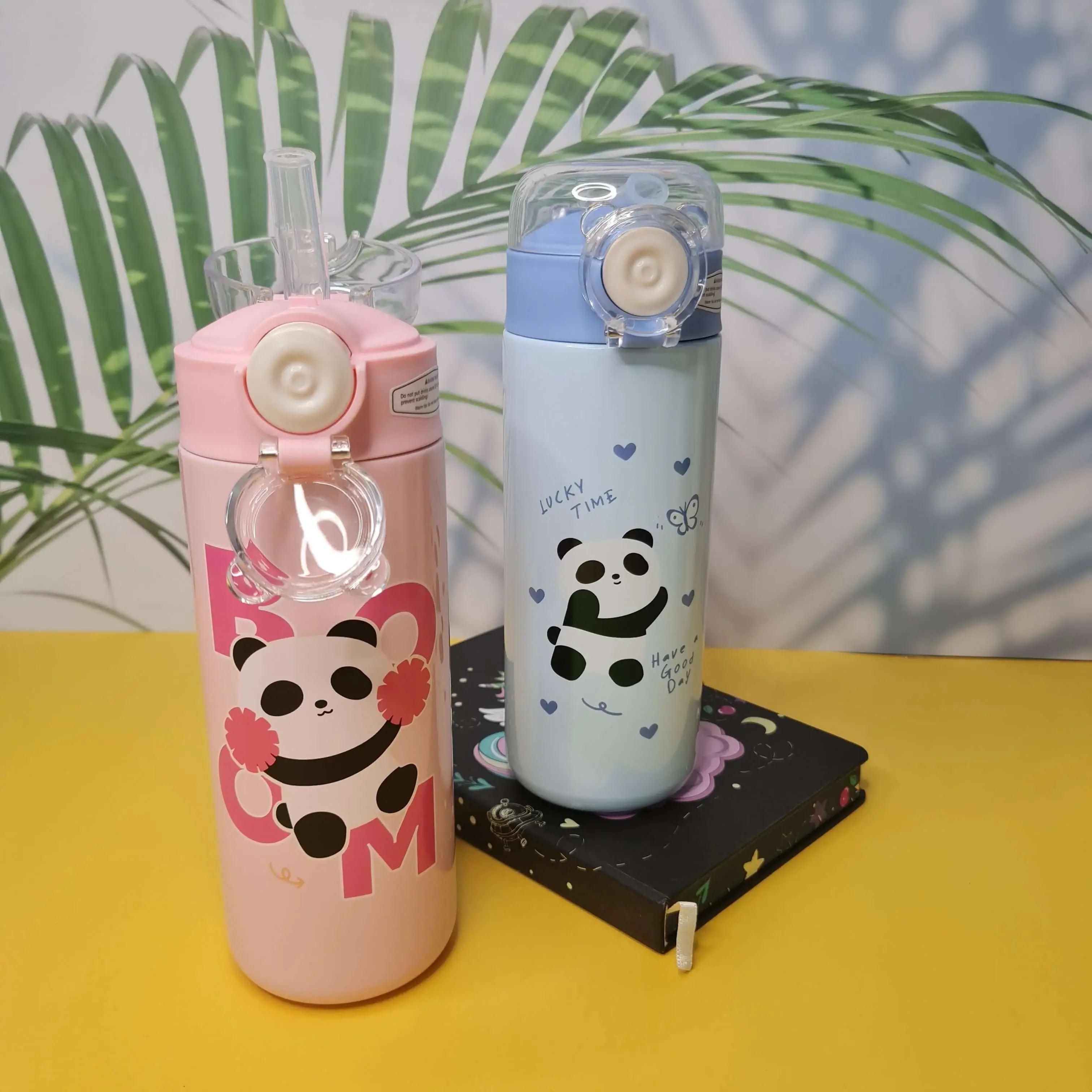 Two panda-themed water bottles on a yellow surface with a leafy background