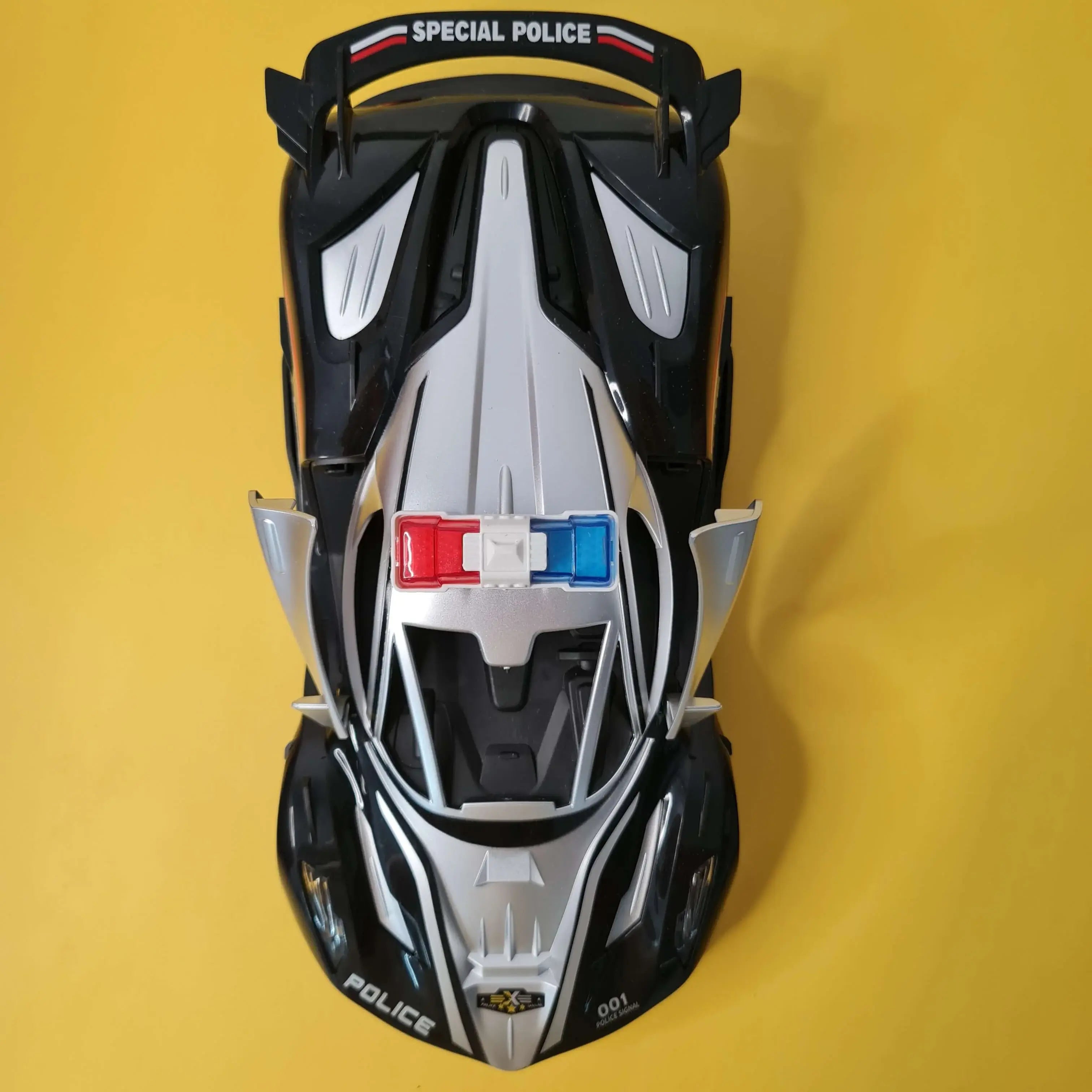 Top-down view of a toy police car on a yellow background
