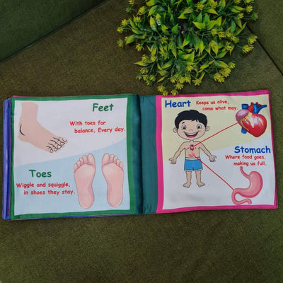 A "My Amazing Body: Head to Toe" fabric book by Kidogen, showing a cartoon child meditating with illustrations of body parts and organs around them.