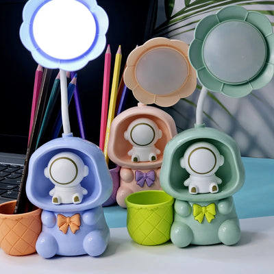 Set of three Usmile Toys Astronaut Teddy Lamps in blue, pink, and green, each featuring a glowing flower-shaped light and a base designed as a convenient pencil holder." www.usmile.com