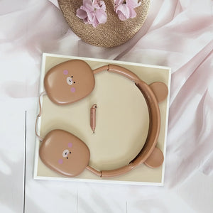 Close-up of pink BuBu Bear wired headphones for kids, showcasing the rabbit-inspired design with bear face on the earcups, a detachable microphone, and the headphones positioned on a white surface with floral accents.      www.usmile.toys