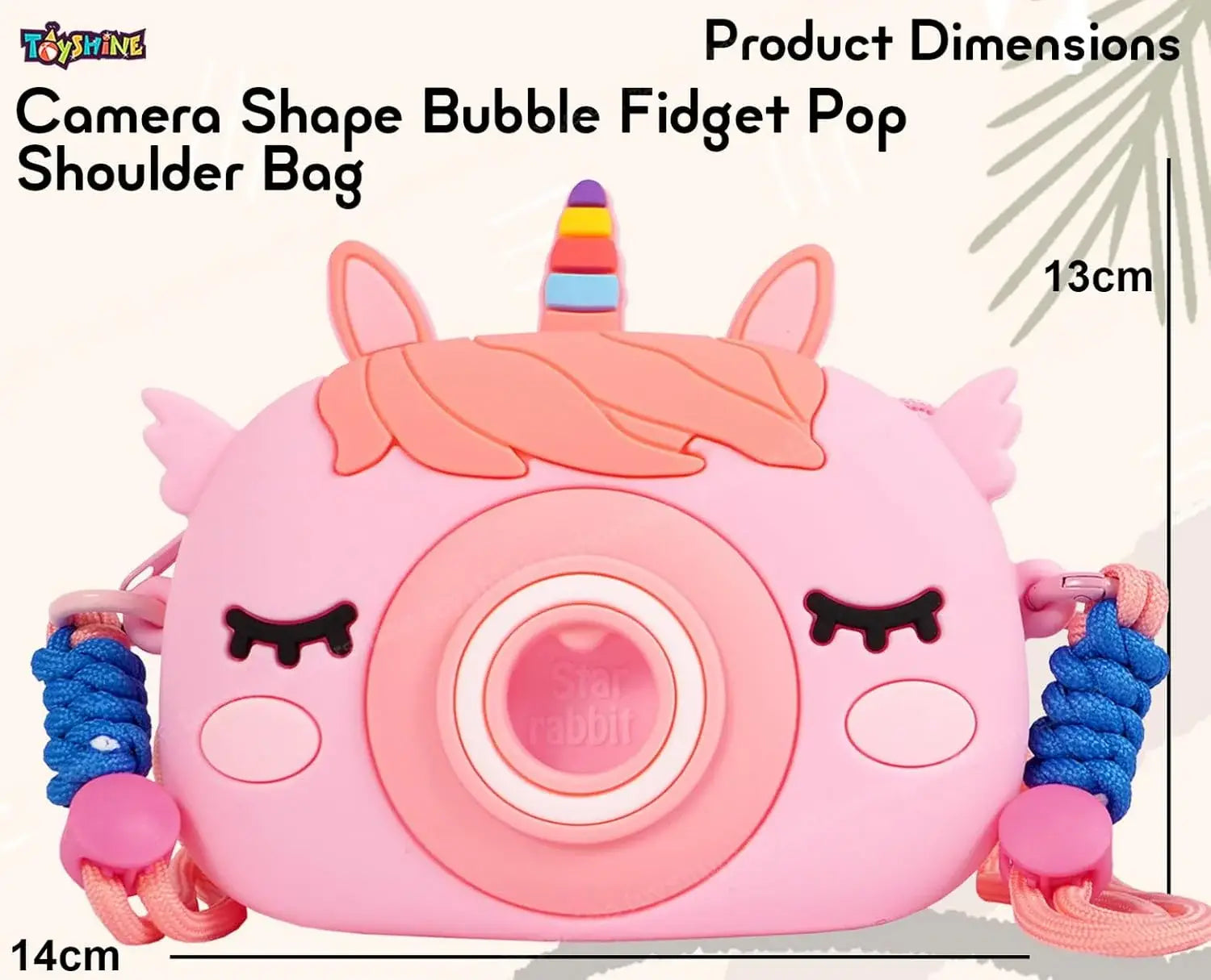 Front view of a 'Kawaii-G' camera-shaped silicone bag for children, in pink with a rainbow unicorn horn, alongside a pink unicorn comb, 'Fruit' keychain, and unicorn keychains."