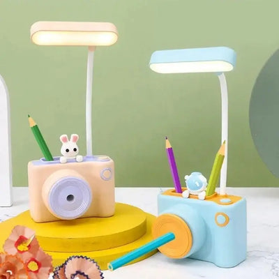 "Two cute camera-shaped study desk LED lamps for kids, one peach and one light blue, each featuring a pencil holder and a built-in pencil sharpener. Ideal for reading and organizing stationery from uSmile.toys." www.usmile.toys