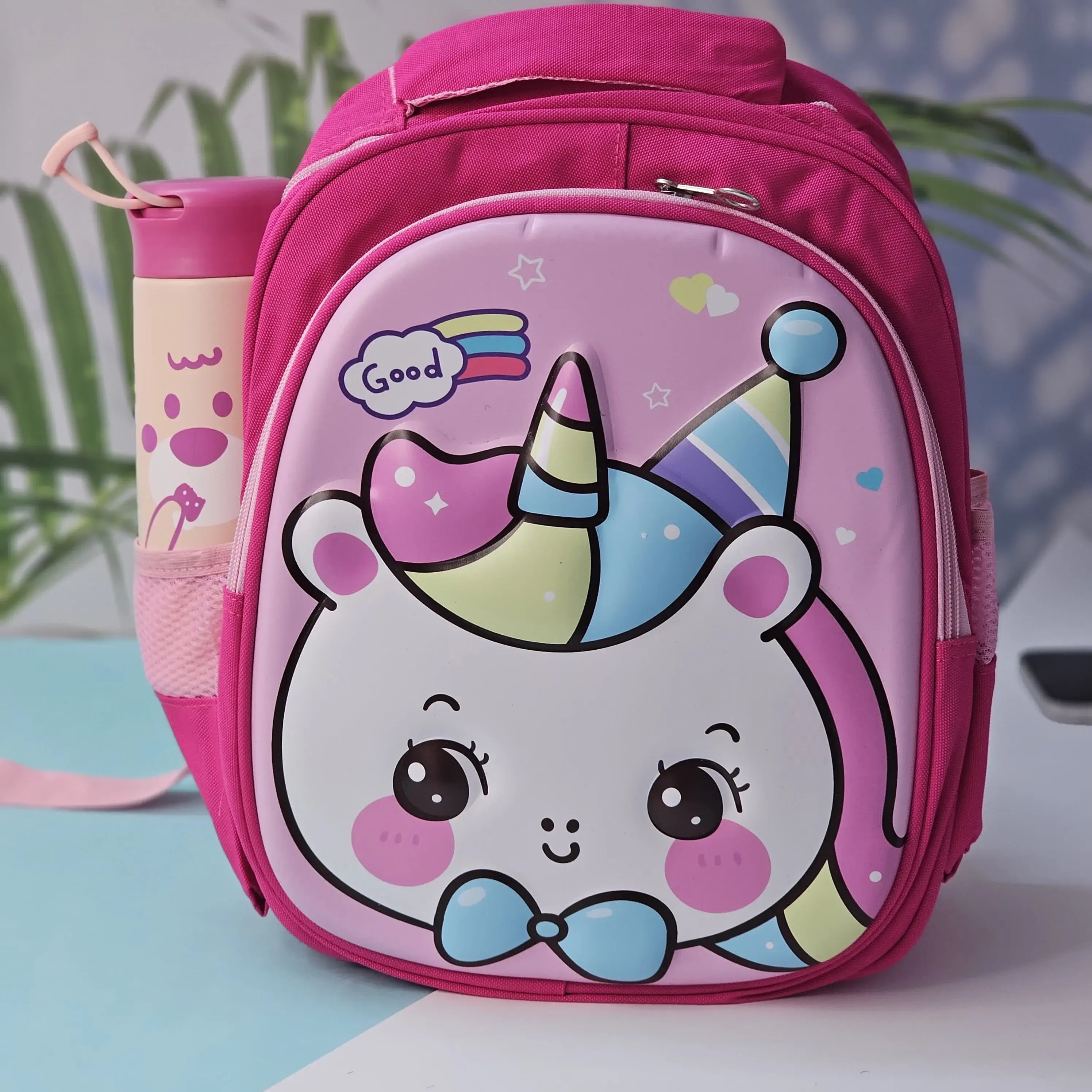Pink cartoon school backpack for children by Usmile Toys, featuring a cute unicorn face with a rainbow horn and a side pocket for a water bottle." www.usmile.com