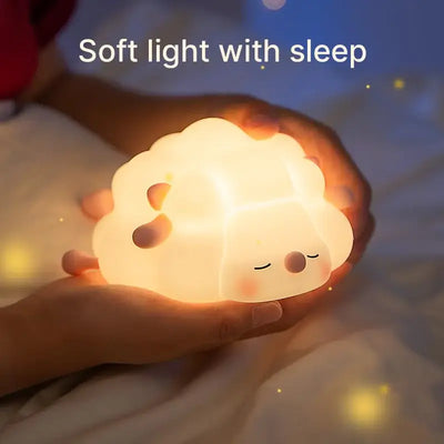 Adorable glowing white silicone night lamp for kids, shaped like a little sleeping sheep with closed eyes and a peaceful expression, resting on a white surface. Ideal for a calming bedtime ambiance from uSmile.toys." www.usmile.toys