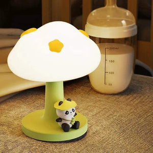 Cute green and white silicone bedside table lamp for kids, with a mushroom-shaped top and a small 'PoPo Panda' figurine sitting at its base. Provides a gentle glow. Ideal for a child's bedroom from uSmile.toys." www.usmile.toys