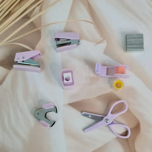 Adorable 9-piece Kawaii mini stationery gift set in pastel purple theme, perfect for school kids and return gift ideas – includes stapler, staple remover, hole puncher, tape holder with tape roll, sharpener, scissor, and a box of staples. Packaged in a beautifully designed cartoon-themed gift box with cute illustrations and soft pink-purple tones. Ideal for girls aged 5 and above who love fun and functional stationery items – available at U Smile Toys India