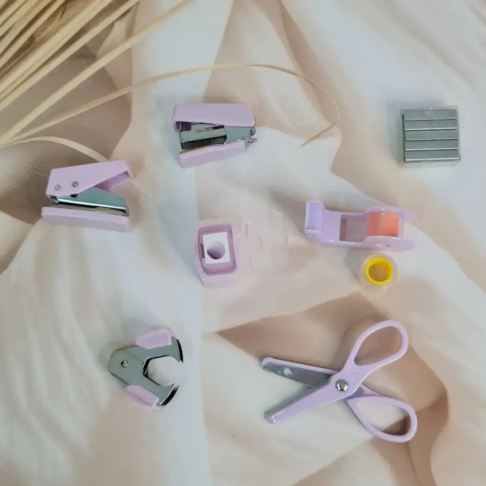 Adorable 9-piece Kawaii mini stationery gift set in pastel purple theme, perfect for school kids and return gift ideas – includes stapler, staple remover, hole puncher, tape holder with tape roll, sharpener, scissor, and a box of staples. Packaged in a beautifully designed cartoon-themed gift box with cute illustrations and soft pink-purple tones. Ideal for girls aged 5 and above who love fun and functional stationery items – available at U Smile Toys India