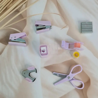 Adorable 9-piece Kawaii mini stationery gift set in pastel purple theme, perfect for school kids and return gift ideas – includes stapler, staple remover, hole puncher, tape holder with tape roll, sharpener, scissor, and a box of staples. Packaged in a beautifully designed cartoon-themed gift box with cute illustrations and soft pink-purple tones. Ideal for girls aged 5 and above who love fun and functional stationery items – available at U Smile Toys India