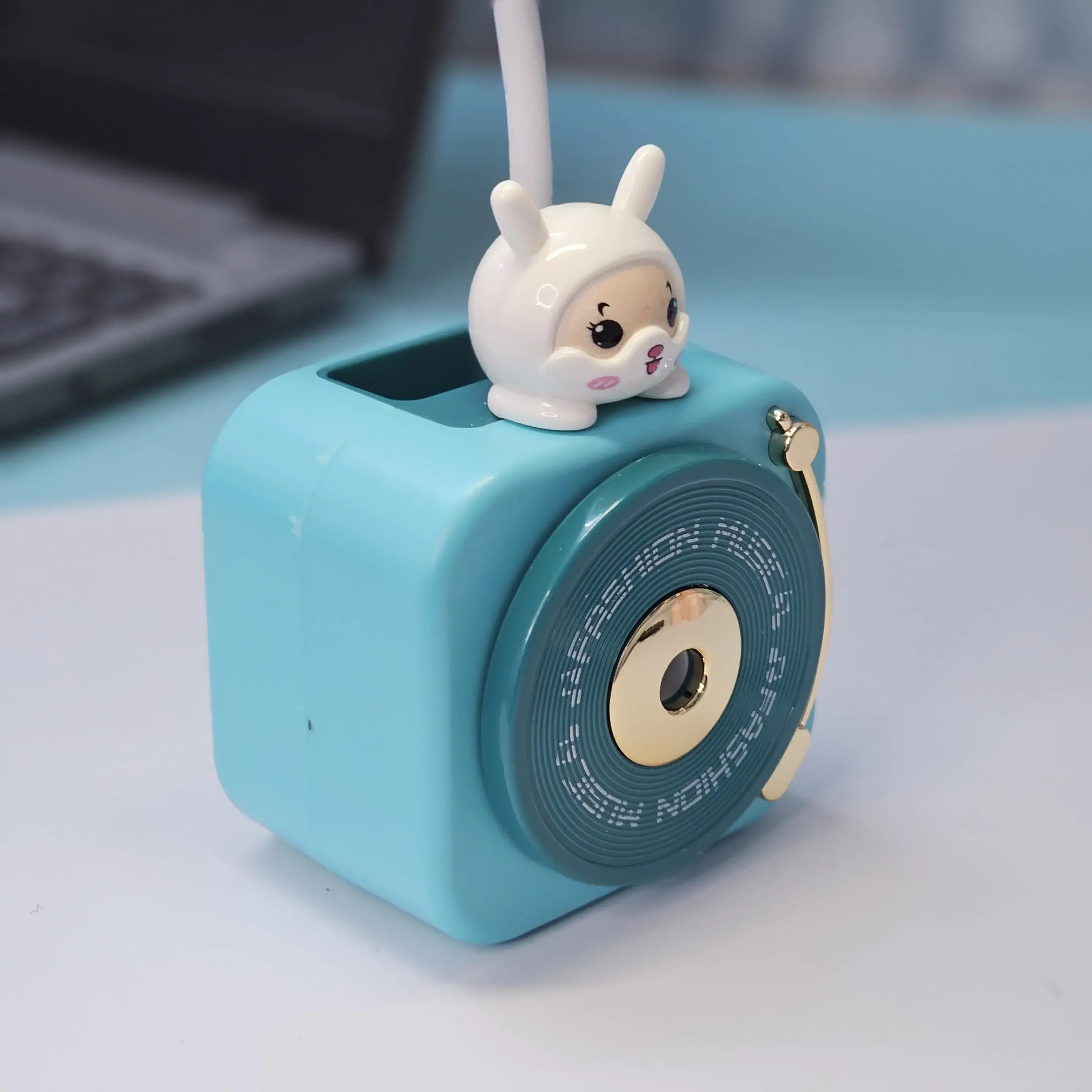 Compact Usmile Toys LED desk lamp with a built-in pencil sharpener and pen holder, perfect for students and kids. This space-saving teal plastic desk light offers bright illumination for reading and drawing, helping children stay organized." www.usmile.toys