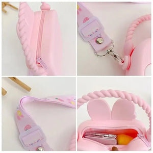 "Front view of a Usmile Toys girls' crossbody purse, made of purple silicone in a charming bunny shape, displayed among tropical leaves."