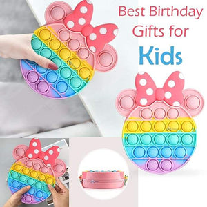 Front view of a Usmile Toys girls' sling bag, designed as a rainbow Pop It fidget toy with a prominent pink Minnie Mouse-style bow and a striped strap." www.usmile.toys