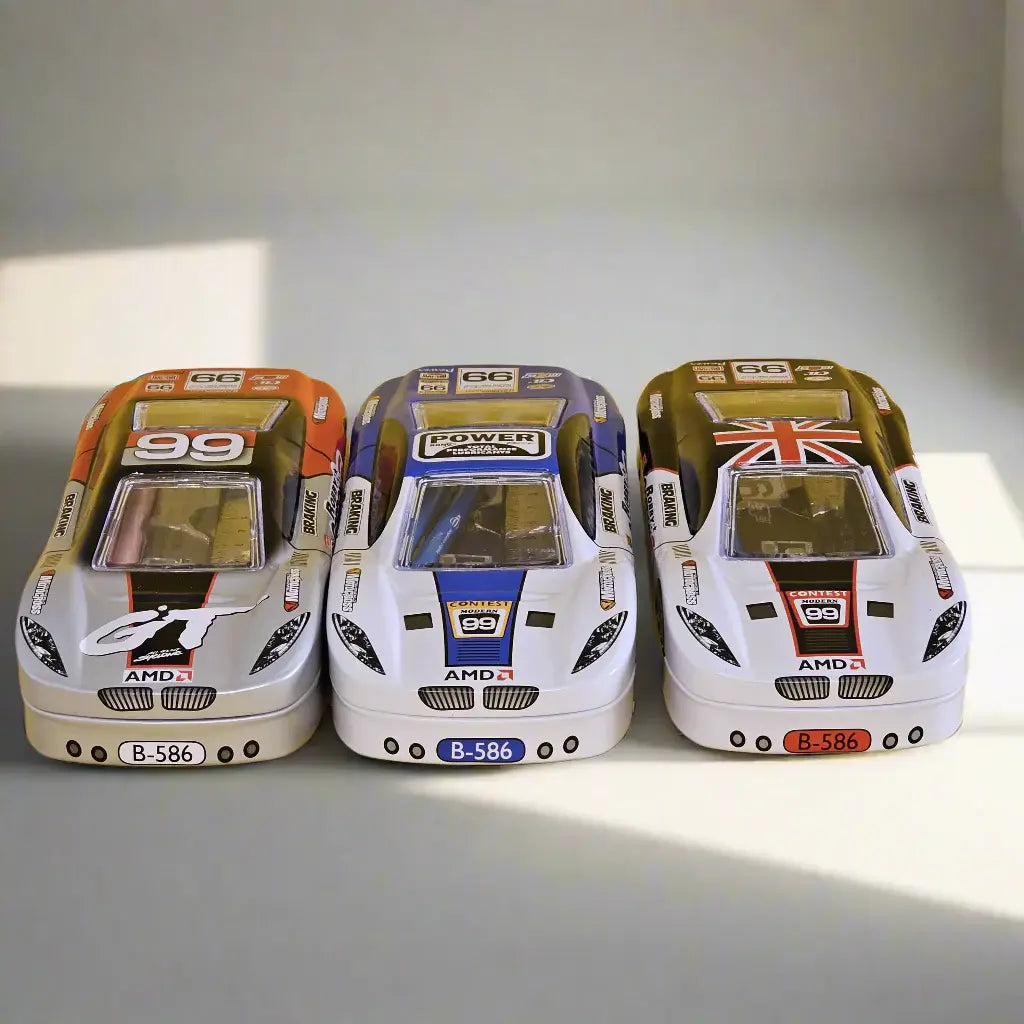 Three race car shaped metal pencil cases for kids, featuring white bodies with orange, blue, and Union Jack accents, each with two layers for organizing stationery. Includes a stationery kit. Ideal for boys from uSmile.toys." www.usmile.toys